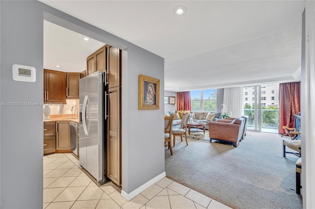 corridor with baseboards, recessed lighting, light tile patterned floors, and light carpet
