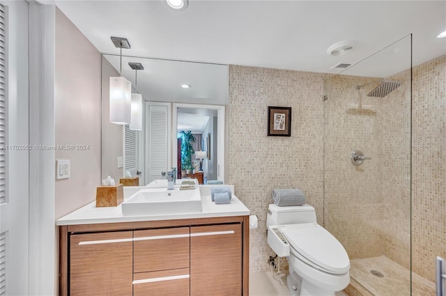 bathroom with a tile shower, vanity, and toilet