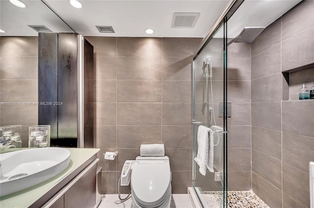 bathroom with toilet, an enclosed shower, tile walls, and vanity