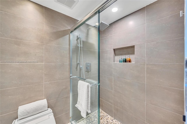 full bathroom featuring toilet, visible vents, and a shower stall