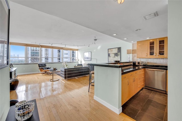 kitchen featuring kitchen peninsula, hardwood / wood-style floors, light brown cabinets, and stainless steel dishwasher