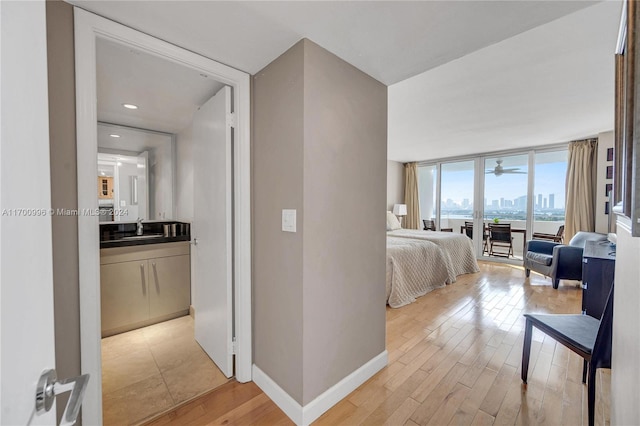 bedroom featuring expansive windows, light hardwood / wood-style floors, and sink