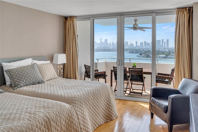 bedroom featuring light hardwood / wood-style floors, a water view, and access to outside