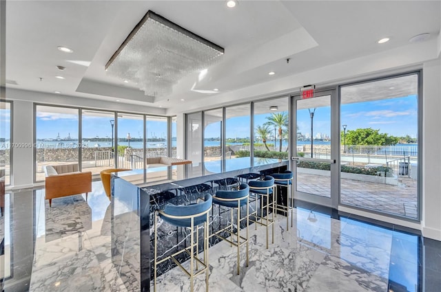 kitchen with a kitchen breakfast bar, a water view, and a raised ceiling