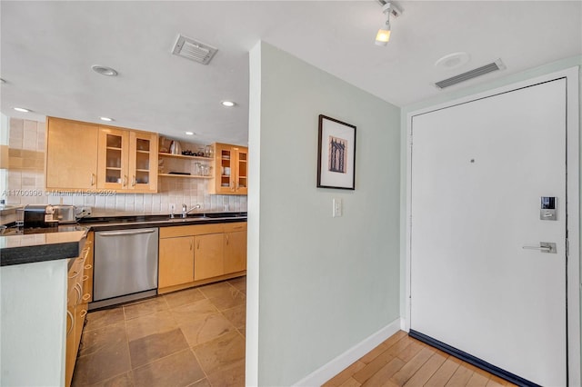 kitchen with backsplash, light hardwood / wood-style flooring, stainless steel dishwasher, and sink