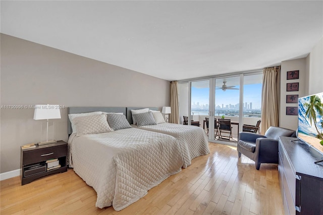 bedroom featuring light wood-type flooring, access to outside, and a wall of windows