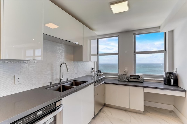 kitchen with decorative backsplash, a water view, dishwasher, and sink