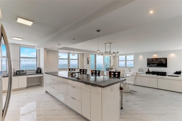 kitchen with pendant lighting, a breakfast bar, a center island, white cabinets, and a water view