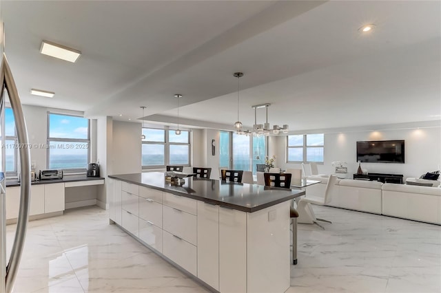 kitchen with a breakfast bar, white cabinetry, a water view, a center island, and hanging light fixtures