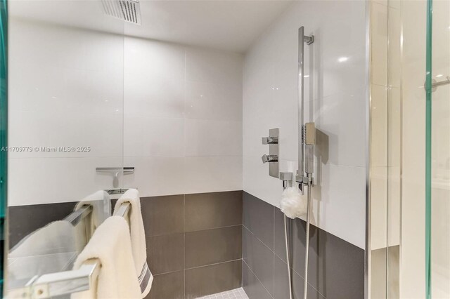 bathroom with an enclosed shower and tile walls