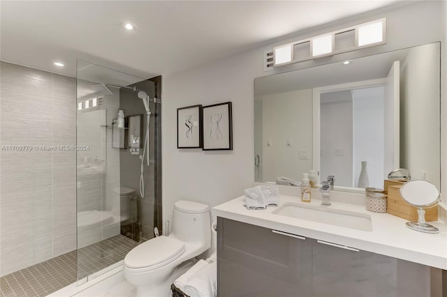 bathroom featuring a tile shower, vanity, and toilet