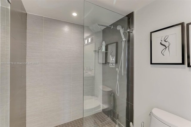 bathroom with tile patterned flooring, a tile shower, and toilet