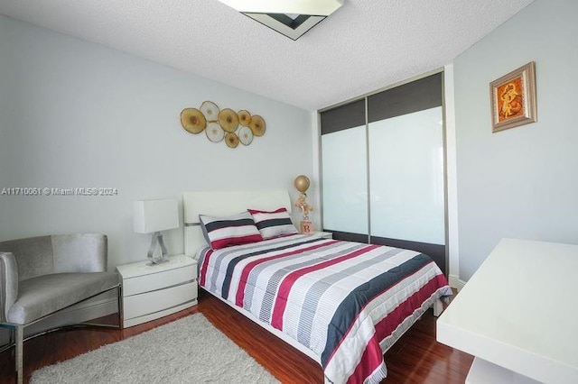 bedroom with dark hardwood / wood-style floors and a textured ceiling