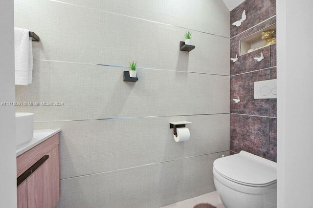 bathroom with vanity, toilet, and tile walls