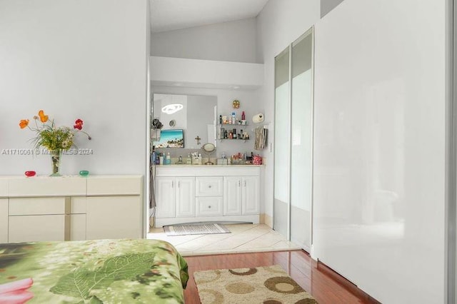 bathroom with hardwood / wood-style floors, vanity, and lofted ceiling