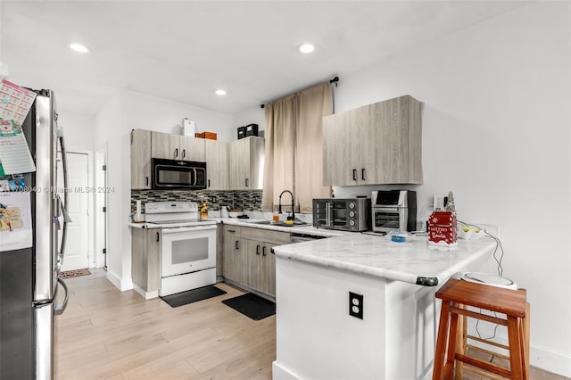 kitchen featuring sink, white electric stove, light hardwood / wood-style floors, kitchen peninsula, and stainless steel refrigerator