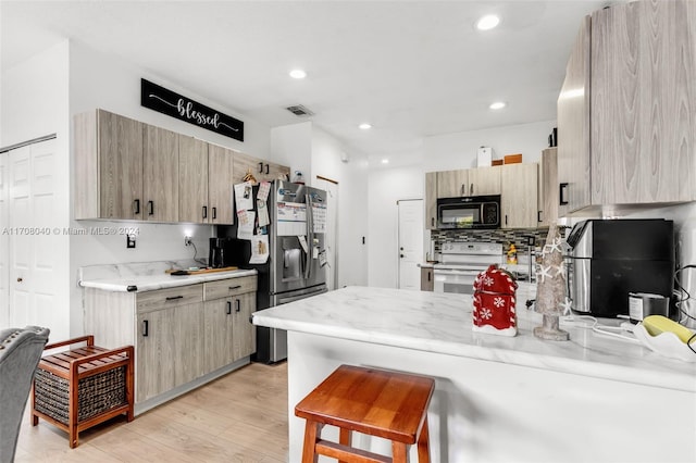 kitchen with light stone countertops, stainless steel fridge, light brown cabinets, light hardwood / wood-style flooring, and white range with electric cooktop