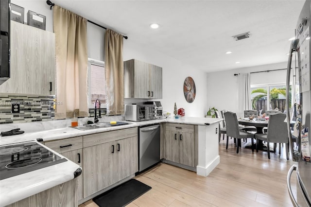 kitchen featuring dishwasher, kitchen peninsula, light hardwood / wood-style flooring, and sink