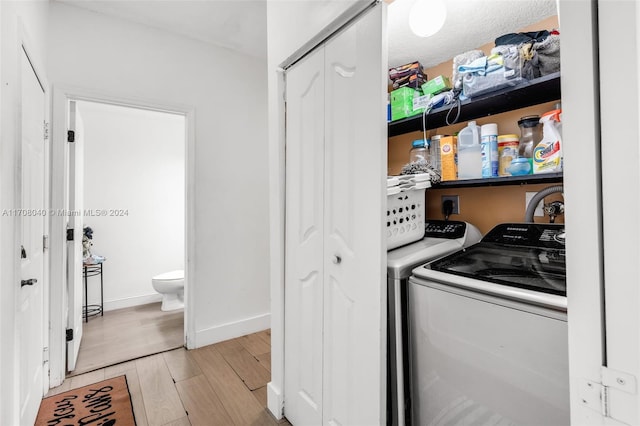 clothes washing area with washer and dryer and light wood-type flooring