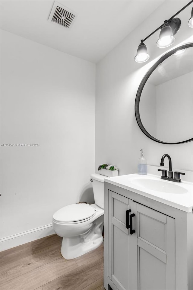 bathroom with hardwood / wood-style floors, vanity, and toilet