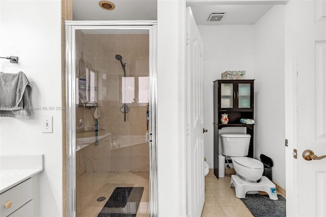 bathroom featuring tile patterned flooring, vanity, an enclosed shower, and toilet