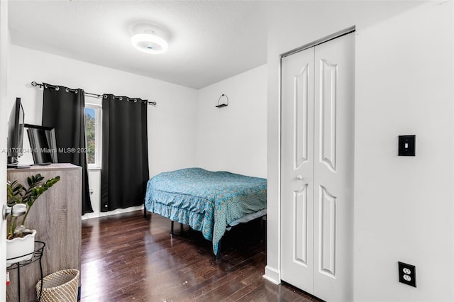 bedroom with dark hardwood / wood-style flooring, a textured ceiling, and a closet