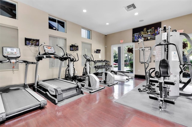 workout area featuring a towering ceiling and wood-type flooring