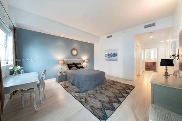 bedroom with ensuite bathroom and light hardwood / wood-style flooring