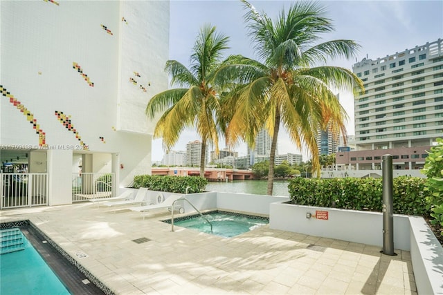 view of swimming pool featuring a water view, a patio, and a hot tub