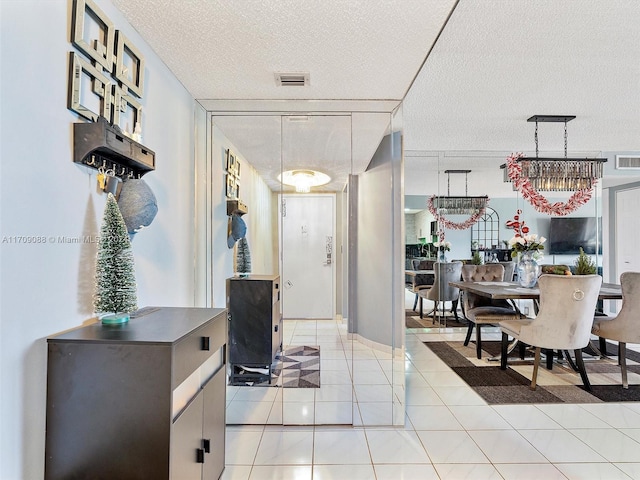 tiled entrance foyer with a textured ceiling and an inviting chandelier