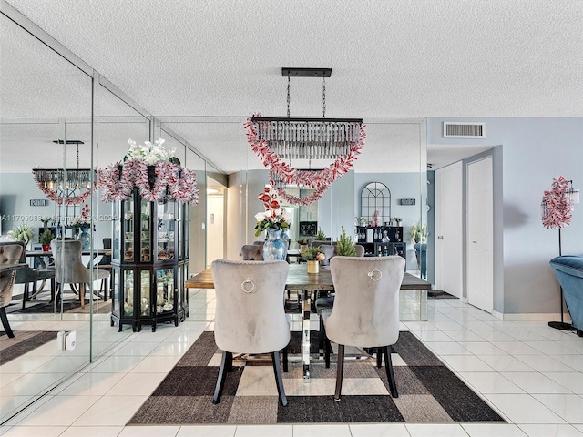 dining area with tile patterned flooring, a chandelier, and a textured ceiling