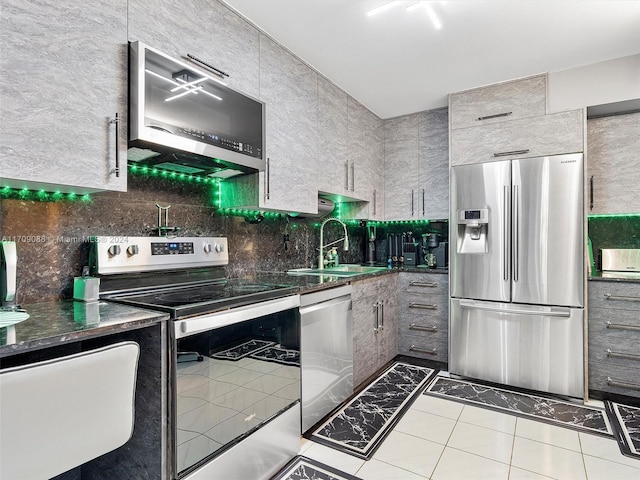 kitchen with backsplash, sink, dark stone countertops, light tile patterned floors, and stainless steel appliances