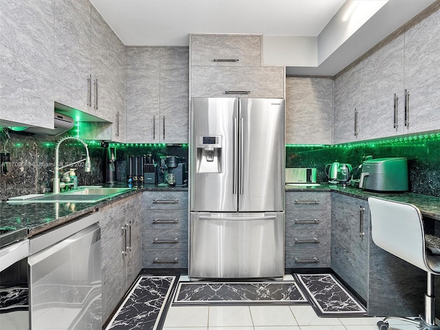 kitchen featuring gray cabinetry, stainless steel appliances, dark stone countertops, and sink