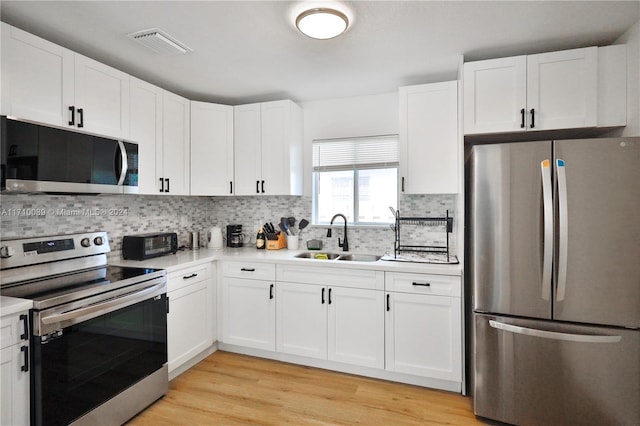 kitchen with white cabinets, stainless steel appliances, light hardwood / wood-style floors, and sink