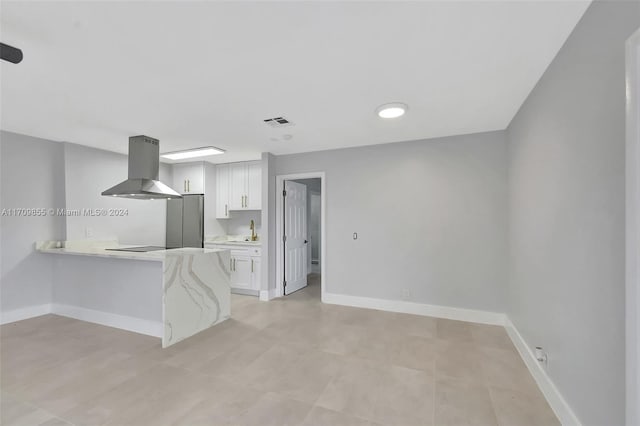 kitchen with kitchen peninsula, light stone countertops, extractor fan, sink, and white cabinetry