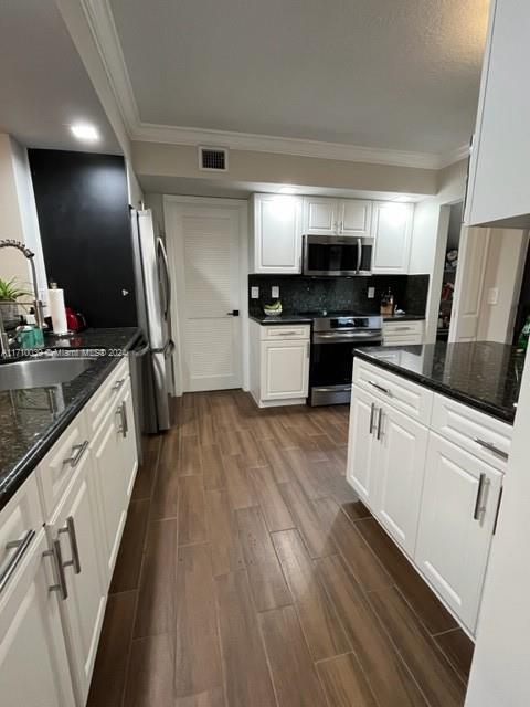 kitchen with white cabinets, stainless steel appliances, dark hardwood / wood-style floors, and sink