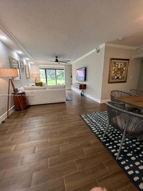 living room featuring ceiling fan, hardwood / wood-style floors, and ornamental molding