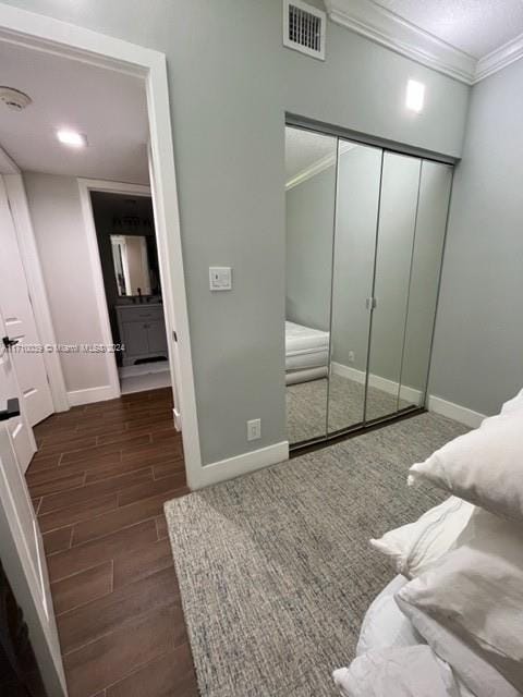 bedroom featuring dark hardwood / wood-style flooring, a closet, and ornamental molding