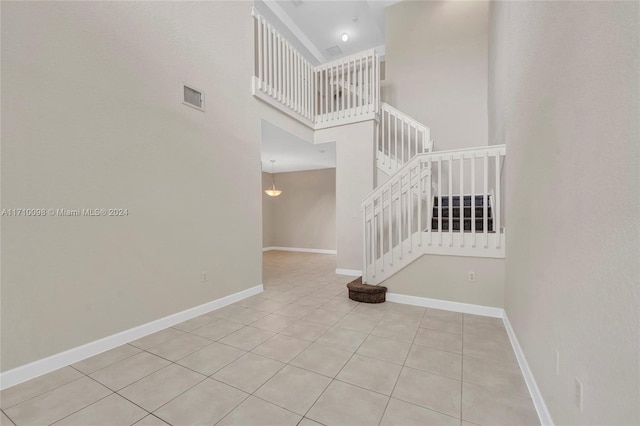 stairway with tile patterned flooring and a towering ceiling