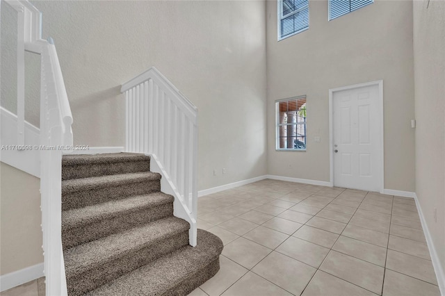 entrance foyer featuring light tile patterned flooring and a towering ceiling