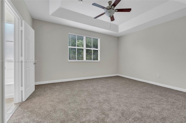 unfurnished bedroom with a raised ceiling, ceiling fan, and light carpet