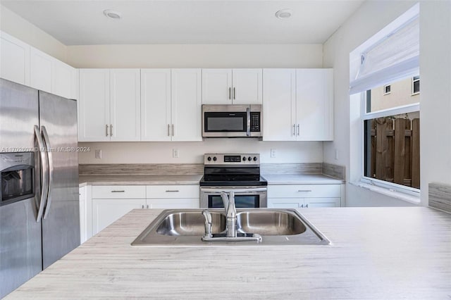 kitchen featuring appliances with stainless steel finishes, white cabinetry, and sink