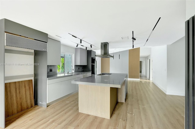 kitchen with island exhaust hood, light hardwood / wood-style floors, a kitchen island, and sink