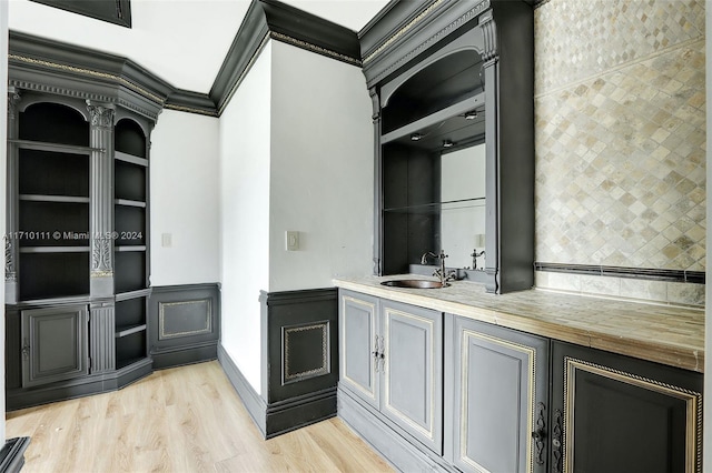 kitchen with crown molding, sink, and light wood-type flooring