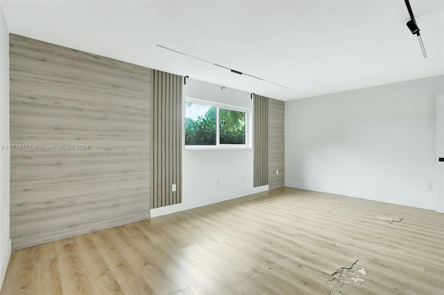 unfurnished room featuring light hardwood / wood-style floors and wooden walls