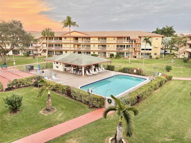 pool at dusk with a yard and a patio area