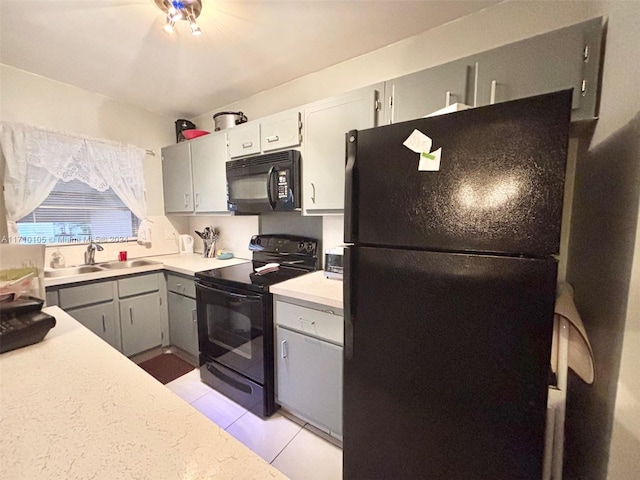 kitchen with light tile patterned floors, sink, gray cabinetry, and black appliances