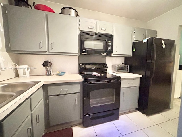 kitchen featuring gray cabinets, light tile patterned floors, and black appliances