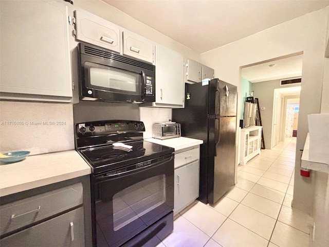 kitchen featuring light tile patterned flooring, white cabinets, and black appliances