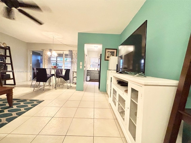 tiled living room with ceiling fan with notable chandelier